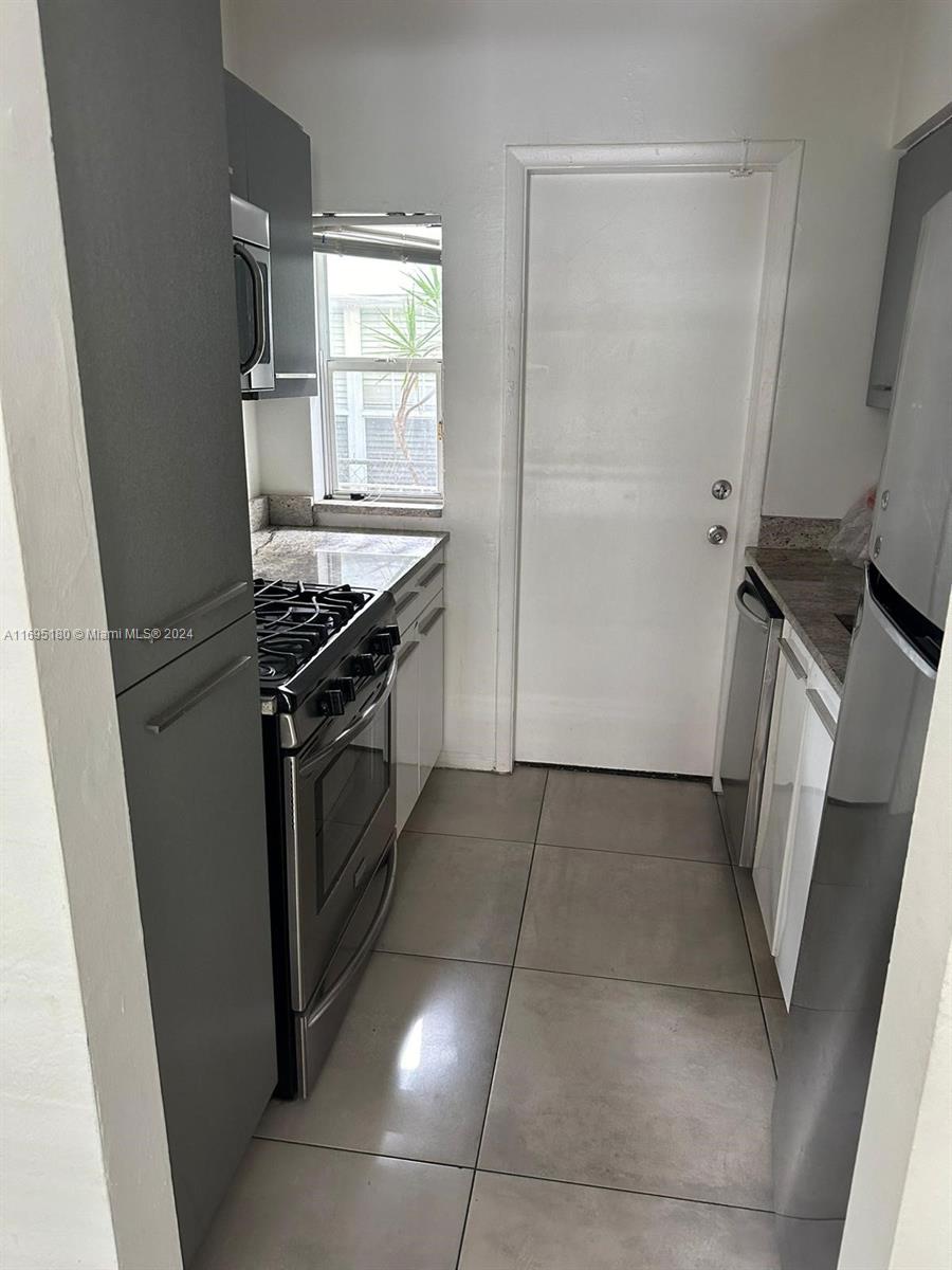 kitchen with tile patterned flooring, white cabinets, and stainless steel appliances