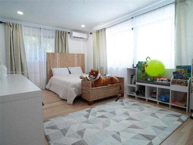 bedroom with light wood-type flooring and a wall mounted AC