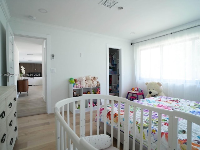 bedroom featuring crown molding and light hardwood / wood-style flooring