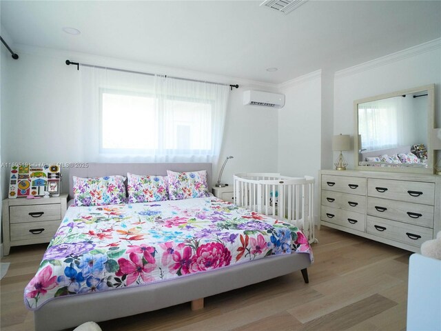 bedroom with light hardwood / wood-style flooring, a wall unit AC, and ornamental molding