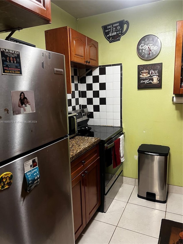 kitchen with appliances with stainless steel finishes, tasteful backsplash, dark stone countertops, and light tile patterned flooring