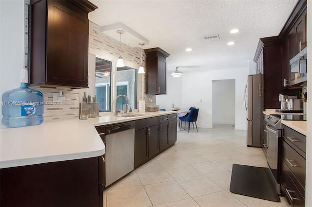 kitchen with sink, hanging light fixtures, a textured ceiling, light tile patterned floors, and appliances with stainless steel finishes