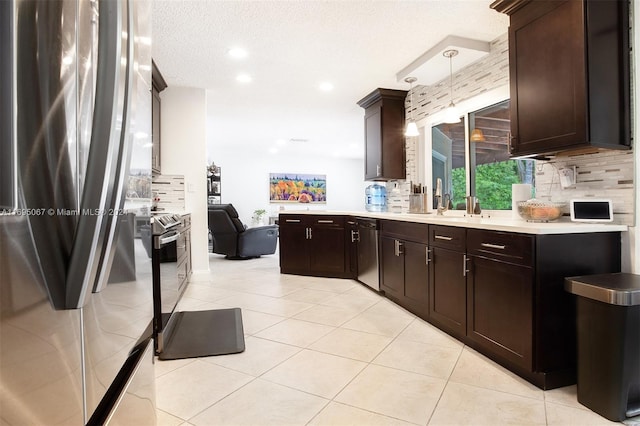 kitchen featuring tasteful backsplash, a textured ceiling, stainless steel appliances, pendant lighting, and light tile patterned floors