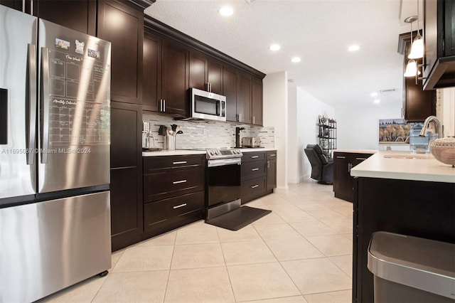 kitchen featuring backsplash, sink, light tile patterned floors, appliances with stainless steel finishes, and dark brown cabinets