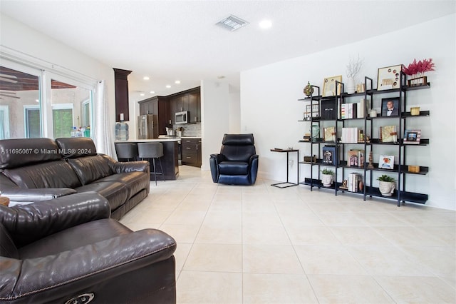 tiled living room featuring ornate columns and a textured ceiling