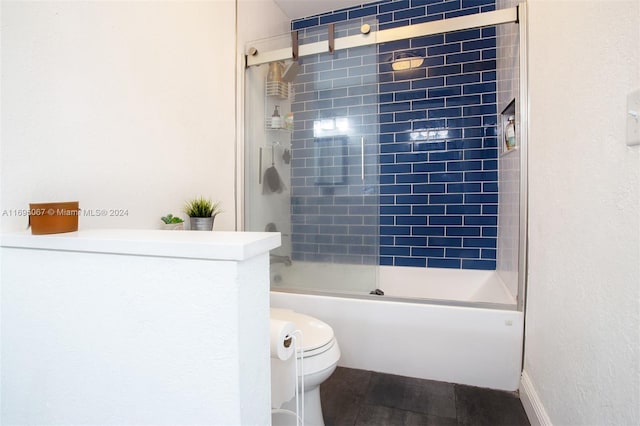 bathroom featuring toilet and bath / shower combo with glass door