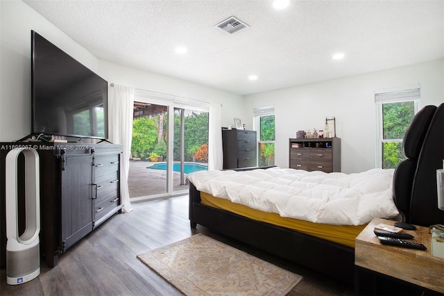 bedroom featuring multiple windows, light hardwood / wood-style flooring, a textured ceiling, and access to exterior