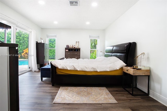 bedroom with access to exterior, dark wood-type flooring, and a textured ceiling