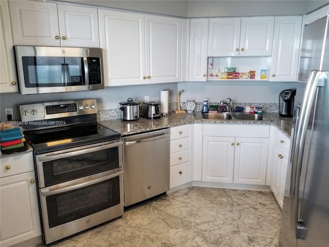 kitchen with sink, white cabinets, dark stone counters, and appliances with stainless steel finishes