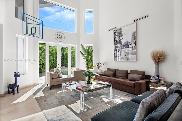 living room featuring french doors, a towering ceiling, and light hardwood / wood-style floors