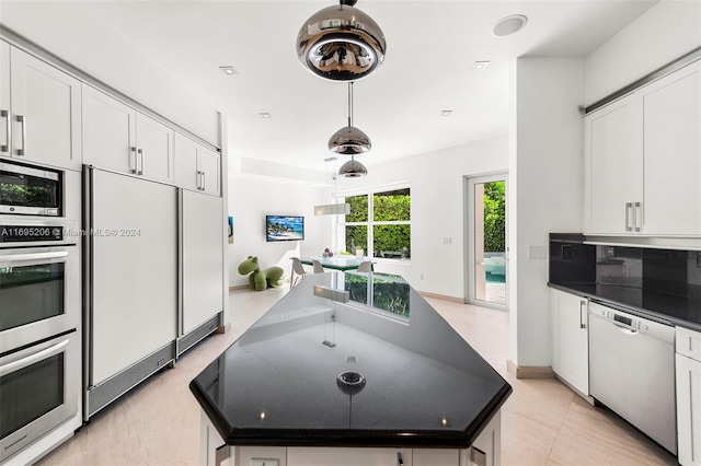 kitchen featuring light tile patterned flooring, dark stone counters, white cabinets, a kitchen island, and stainless steel appliances