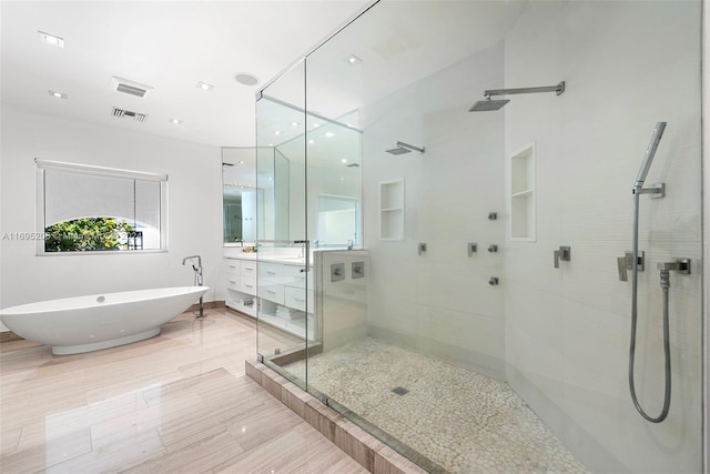 bathroom featuring plus walk in shower, hardwood / wood-style floors, and vanity