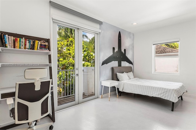 bedroom with concrete floors, access to outside, and multiple windows