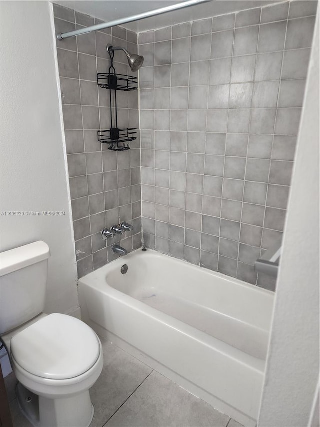 bathroom featuring tile patterned flooring, tiled shower / bath, and toilet