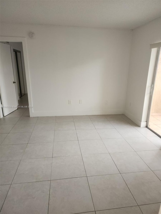 unfurnished room featuring a textured ceiling and light tile patterned flooring