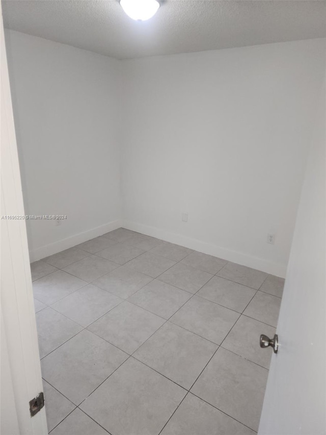 empty room featuring light tile patterned floors and a textured ceiling