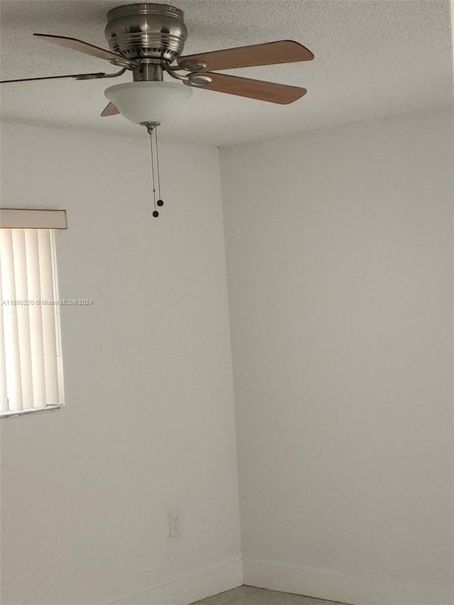 unfurnished room with ceiling fan and a textured ceiling