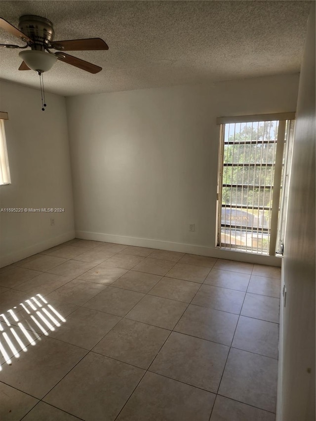 tiled empty room featuring ceiling fan and a textured ceiling