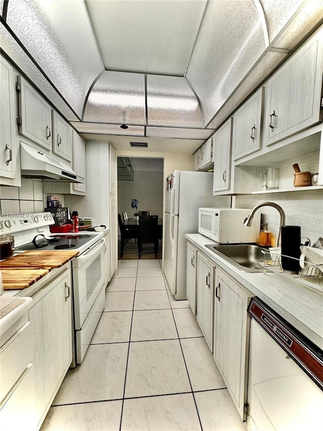 kitchen featuring backsplash, sink, light tile patterned floors, and white appliances