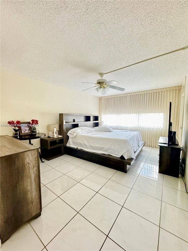 tiled bedroom with ceiling fan and a textured ceiling