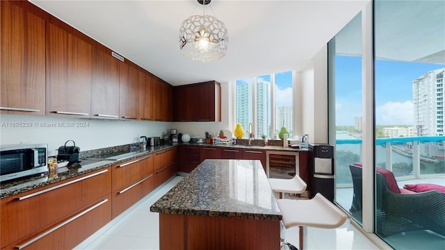 kitchen with pendant lighting, plenty of natural light, dark stone countertops, and sink