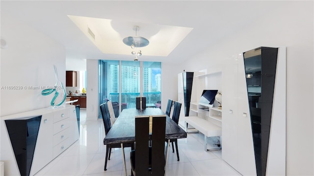 tiled dining room featuring a raised ceiling