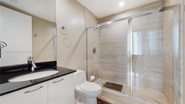 bathroom with a shower with door, vanity, and toilet