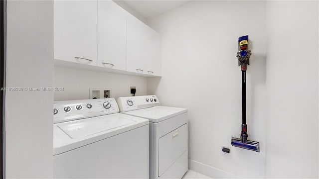 washroom with cabinets, washing machine and dryer, and light tile patterned flooring