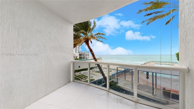 balcony with a water view and a view of the beach