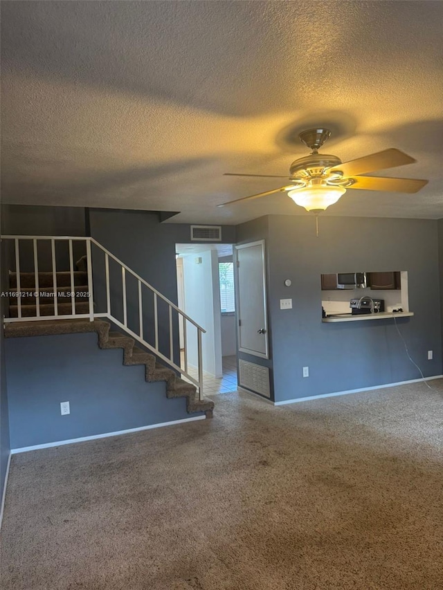 unfurnished living room featuring ceiling fan and a textured ceiling