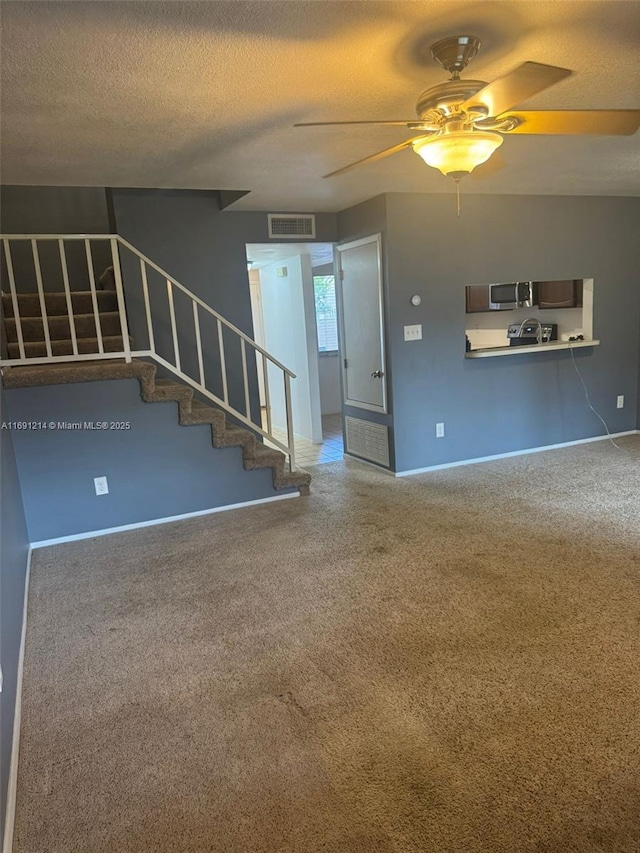 unfurnished living room featuring a textured ceiling and ceiling fan