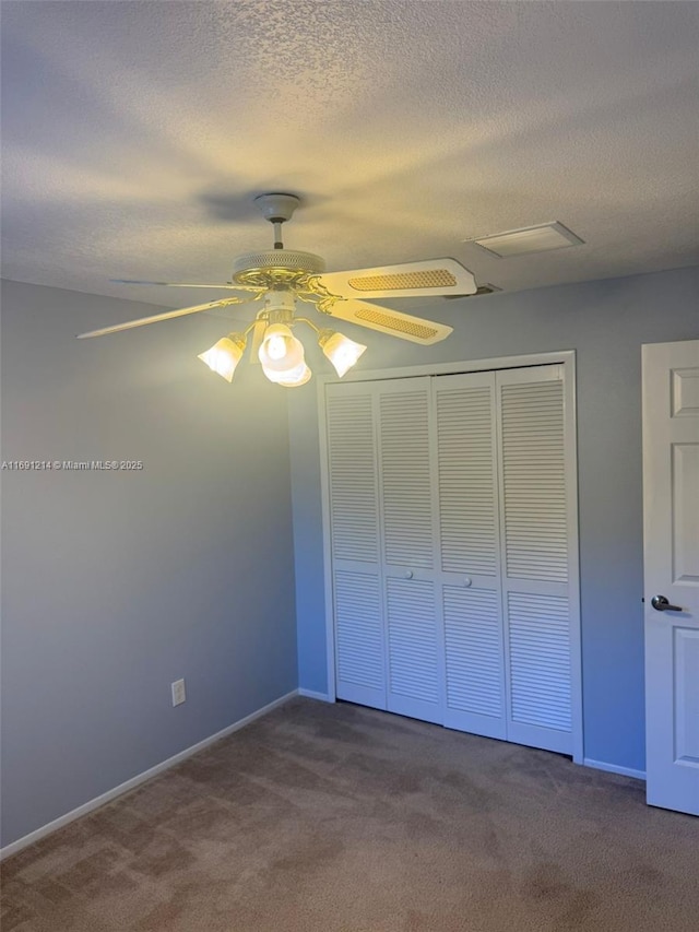 unfurnished bedroom with a closet, ceiling fan, carpet flooring, and a textured ceiling