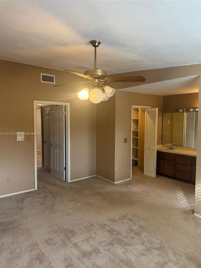 interior space with ceiling fan, light colored carpet, a textured ceiling, and sink