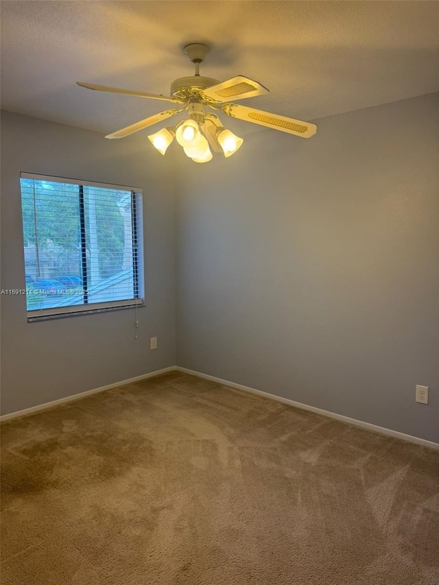 unfurnished room with ceiling fan and carpet