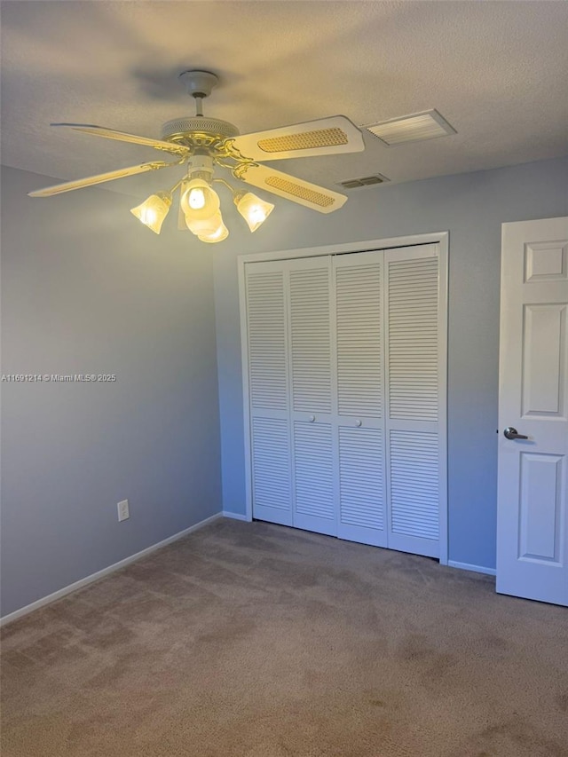 unfurnished bedroom with a closet, ceiling fan, a textured ceiling, and carpet floors