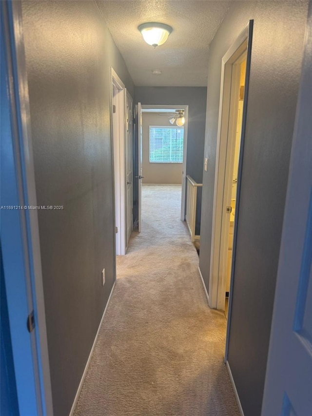 hall with a textured ceiling and light carpet