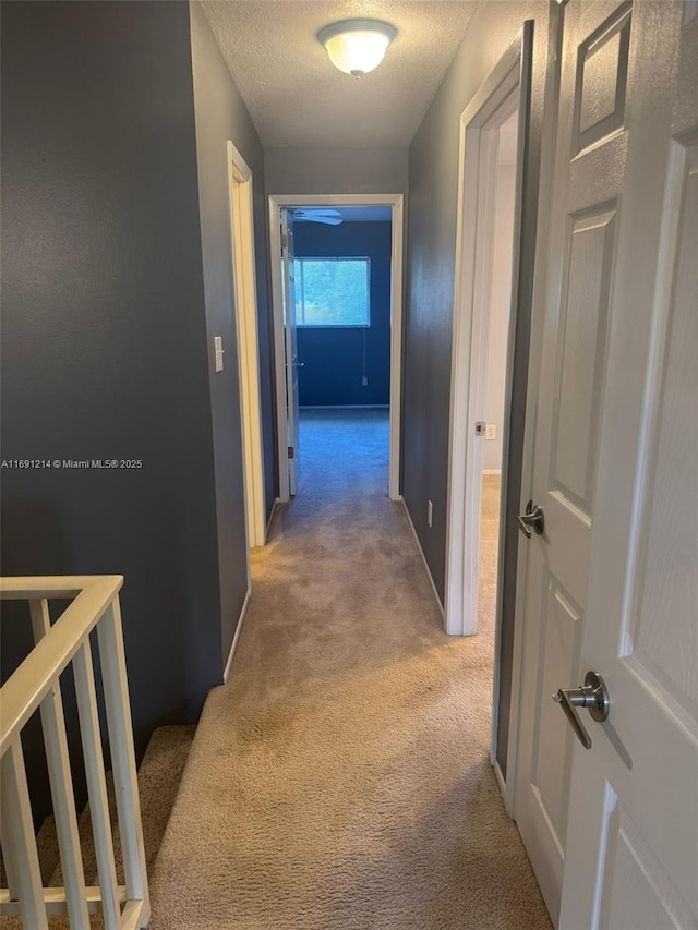 corridor featuring a textured ceiling and light carpet