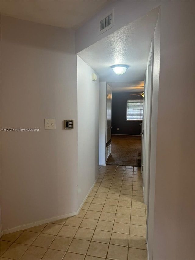 corridor with light tile patterned flooring and a textured ceiling