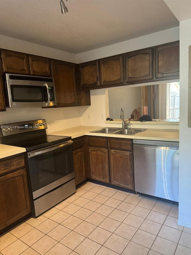 kitchen featuring sink, dark brown cabinetry, appliances with stainless steel finishes, and light tile patterned flooring