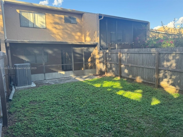 rear view of property with a sunroom, central AC unit, and a yard