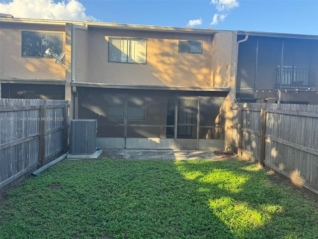 back of house featuring central AC unit, a yard, and a sunroom