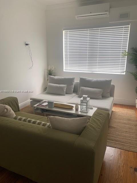 living room featuring hardwood / wood-style floors, a wall unit AC, and ornamental molding