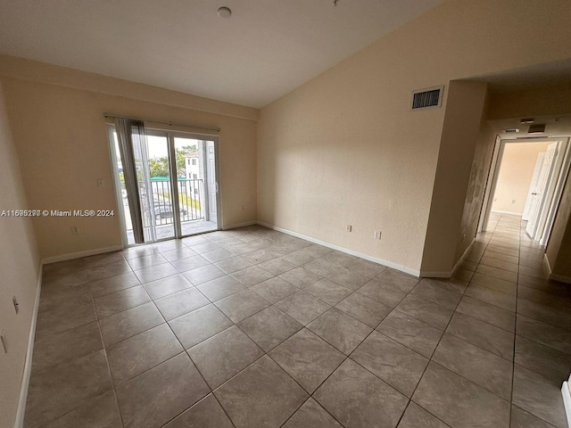 tiled spare room with lofted ceiling