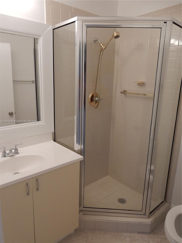 bathroom with tile patterned floors, vanity, and an enclosed shower