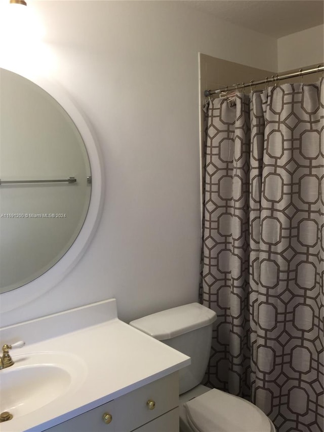 bathroom featuring curtained shower, vanity, and toilet