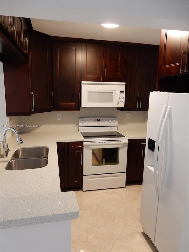 kitchen featuring light stone countertops, white appliances, dark brown cabinetry, sink, and light tile patterned floors