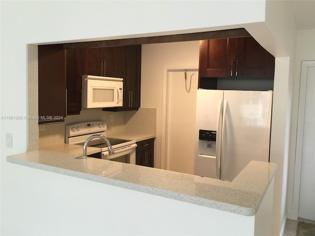 5051 W Oakland Park Blvd Unit 302, Lauderdale Lakes, FL 33313 - kitchen featuring white appliances, light stone counters, dark brown cabinets, and a peninsula