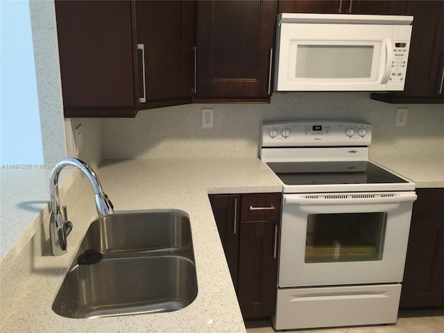 kitchen featuring light stone countertops, white appliances, dark brown cabinetry, and sink