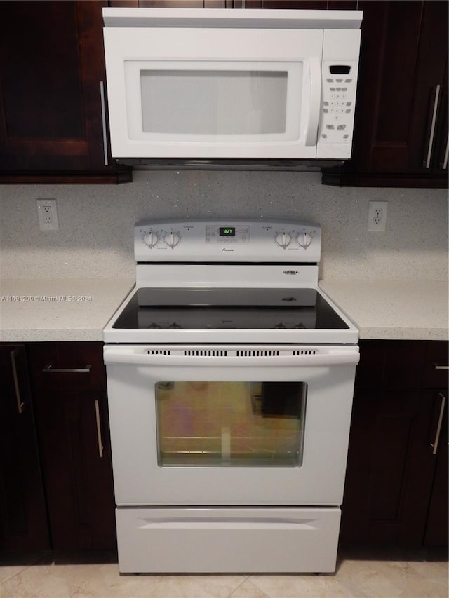 kitchen with dark brown cabinets, white appliances, and tasteful backsplash