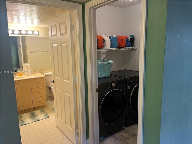 washroom with separate washer and dryer, sink, light tile patterned floors, and a textured ceiling